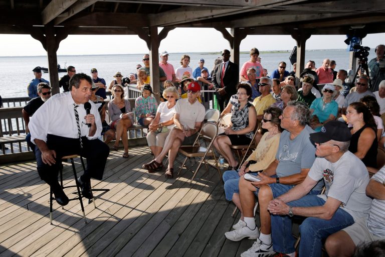 New Jersey Gov. Chris Christie, seated left, answers a question about pensions from retired Stafford Township, N.J., Police Chief Larry Parker, right front, as Christie addressed a gathering Tuesday, July 22, 2014, in Long Beach Township, N.J. (AP/Mel Evans)
