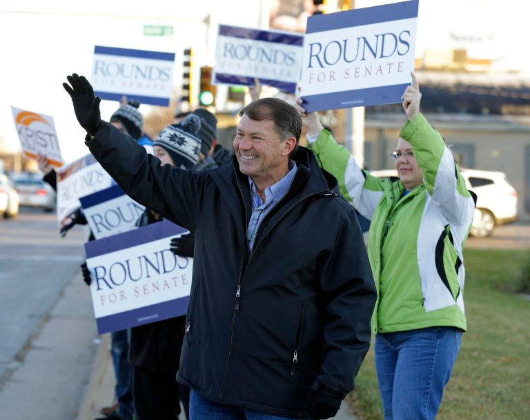 Republican U.S. Senate candidate Mike Rounds campaigns with supporters during the morning commute in Sioux Falls, S.D., Tuesday, Nov. 4, 2014. (AP Photo/Michael Conroy)