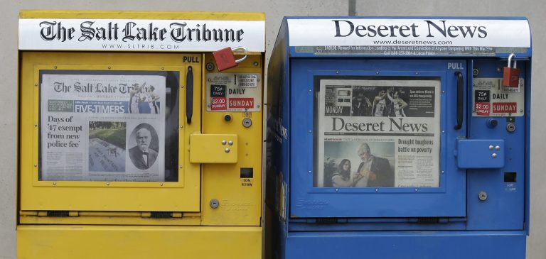 FILE - In this June 16, 2014, file photo, the Salt Lake Tribune and Deseret News newspaper boxes await customers, in Salt Lake City. A federal judge will consider a request Monda, Sept. 8, 2014, from Salt Lake City's two daily newspapers to dismiss a lawsuit challenging their joint-operating agreement. U.S. District Judge Clark Waddoups will hear arguments Monday but it's unclear when he will rule on the issue. (AP Photo/Rick Bowmer, File)