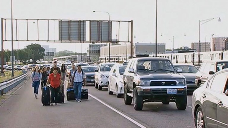 This photo from video provided courtesy of WMAQ-TV in Chicago shows air travelers wheeling their luggage toward Chicago's O'Hare International Airport Tuesday, July 1, 2014, after sudden rains flooded the Kennedy Expressway, a major thoroughfare that runs to the airport. Desperate travelers were forced to get out of taxis and haul their luggage the rest of the way to the airport. (AP Photo/Courtesy of WMAQ-TV Chicago)