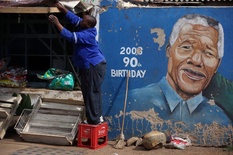   A man readies his shop near a mural showing former South African President Nelson Mandela in the Soweto area of Johannesburg, South Africa, Sunday, Dec. 9, 2012. South Africaâs presidency says that Mandela, 94, was admitted to a hospital Saturday in the nationâs capital for tests. (AP Photos/Jon Gambrell)  