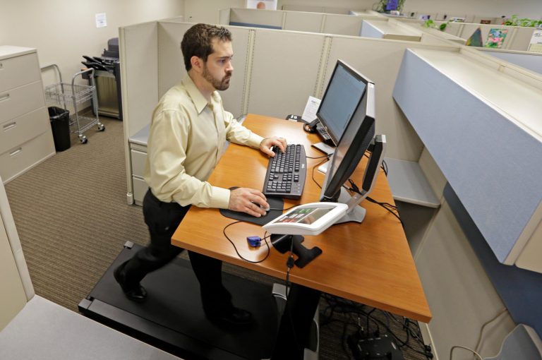   Josh Baldonado, an administrative assistant at Brown & Brown Insurance, works at a treadmill desk in the firms offices in Carmel, Ind., Wednesday, Aug. 28, 2013. Workers sign up for 30 slots not he treadmills and have their phone and computer transferred to the workstations. Being glued to your desk is no longer an excuse for not having time to exercise as a growing number of Americans are standing, walking and even cycling their way through the work day at treadmill desks, standup desks or other moving work stations. (AP Photo/Michael Conroy)  