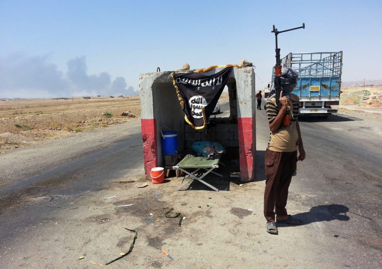 FILE - In this file photo taken Thursday, June 19, 2014, an al-Qaida-inspired militant stands guard at a checkpoint captured from the Iraqi Army outside Beiji refinery, some 250 kilometers (155 miles) north of Baghdad, Iraq. The al-Qaida breakaway group that has seized much of northern Syria and huge tracks of neighboring Iraq formally declared the creation of an Islamic state on Sunday, June 29, in the territory under its control. (AP Photo, File)