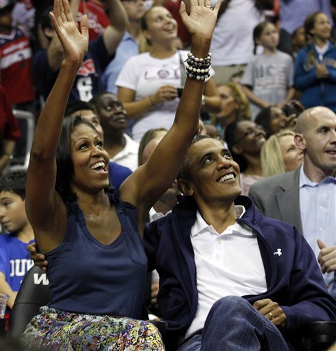 President Barack Obama, right, and first lady Michelle Obama, look up at themselves on the large in-house video screen, while attending the first half of Team USA and Brazil in an Olympic men's exhibition basketball game Monday, July 16, 2012, in Washington. Team USA won 80-69. (AP Photo/Alex Brandon)