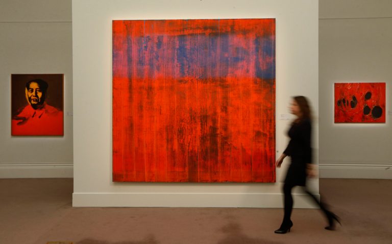 A Sotheby's employee poses for photographers with 'Wand' by Gerhard Richter, center, 'Mao' by Andy Warhol, left, and 'Rosso Plastica' by Alberto Burri on display at the auction house in London, Wednesday, Jan. 29, 2014. The paintings are to be auctioned in Contemporary Art sale on Feb. 12 with an estimated price of  15 to 25 million pounds (US$24.8 to 41.4 million or 18.2 to 30.3 million euro) for 'Wand', 5.5 to 7.5 million pounds (US$9.1 to 12.4 million or 6.7 to 9.1 million euro) for 'Mao' and 2 to 3 million pounds (US$3.3 to 5 million or 2.4 to 3.6 million euro) for 'Rosso Plastica'. (AP Photo/Sang Tan)