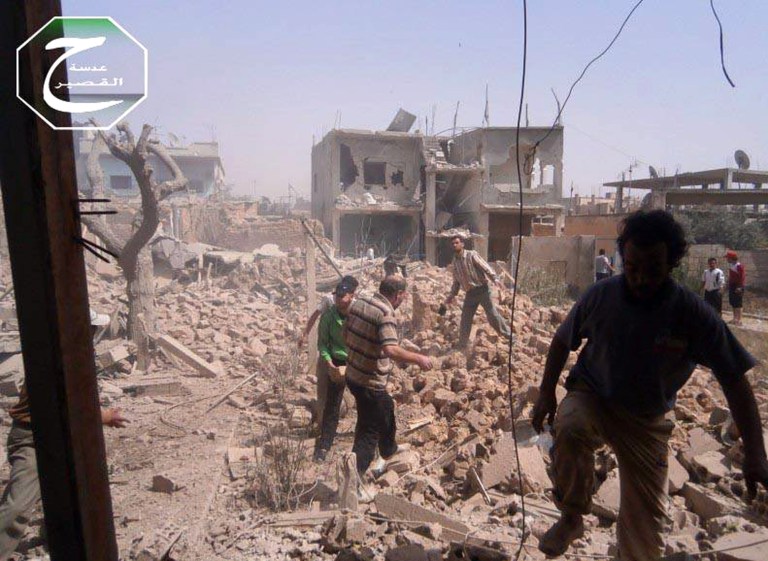 In this Saturday, May 18, 2013 citizen journalism image provided by Qusair Lens which has been authenticated based on its contents and other AP reporting, shows Syrians inspecting the rubble of damaged buildings due to government airstrikes, in Qusair, Homs province, Syria. The town of Qusair has been besieged for weeks by regime troops and pro-government gunmen backed by the Lebanese militant Hezbollah group. The siege is part of a withering offensives forces loyal to Syrian President Bashar Assad have been pushing in recent weeks to regain control of the towns and villages along the Lebanese frontier. (AP Photo/Qusair Lens)