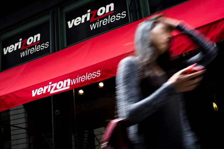 FILE - In this Thursday, June 6,  2013, file photo, a pedestrian uses her cell phone as she passes a Verizon Wireless store on Broadway in Lower Manhattan, in New York.  Verizon Communications Inc. reports quarterly financial results before the market opens on Tuesday, Jan. 21, 2014 (AP Photo/John Minchillo, File)