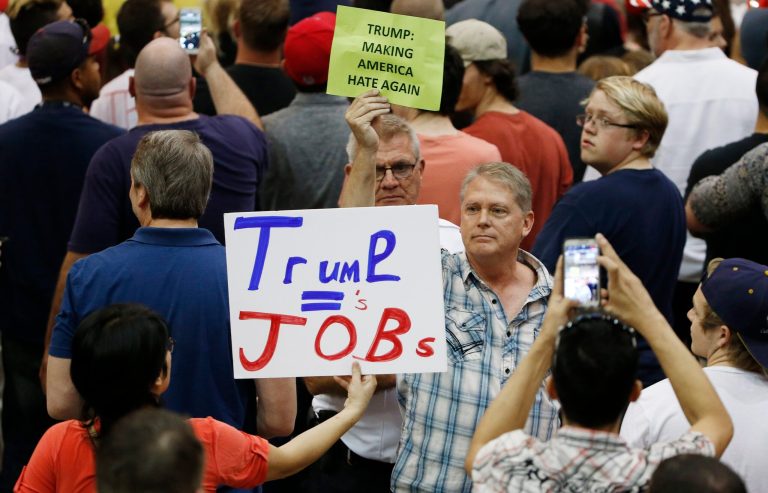 A supporter of Republican presidential candidate Donald Trump, left, holds up a sign in front of an anti-Trump protester as the candidate speaks during a campaign rally Saturday, March 19, 2016, in Tucson, Ariz. (AP Photo/Ross D. Franklin)