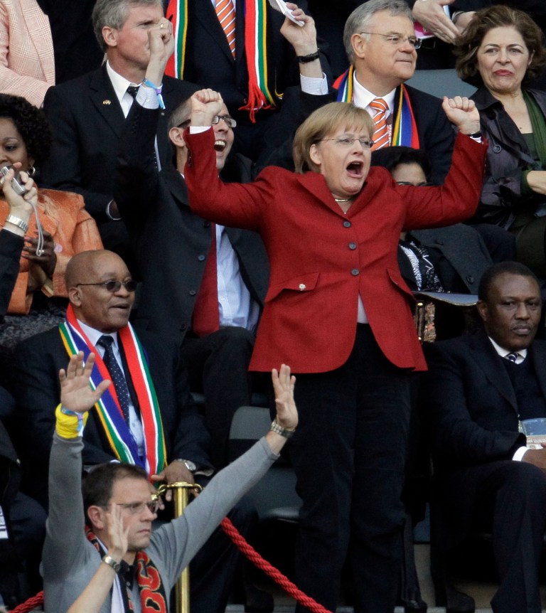 German Chancellor Angela Merkel celebrates after Germany's Thomas Mueller scored as South African President Jacob Zuma sits beside her, during the World Cup quarterfinal soccer match between Argentina and Germany at the Green Point stadium in Cape Town, South Africa, Saturday, July 3, 2010.  (AP Photo/Gero Breloer)