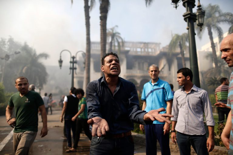 An Egyptian man reacts as firefighters battle flames at the Giza governorate buildings that were stormed and torched by angry supporters of Egypt's ousted president in Cairo on Thursday. (AP/Hassan Ammar)