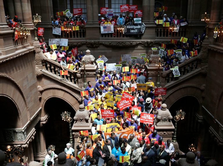 People rally for an increase in the minimum wage on the Great Western Staircase at the Capitol on Tuesday, June 17, 2014, in Albany, N.Y. Several hundred fast-food workers and other low-wage employees from around New York gathered to pressure lawmakers to raise the minimum wage from $8 to $10.10 an hour and let local cities raise it even higher. (AP Photo/Mike Groll)