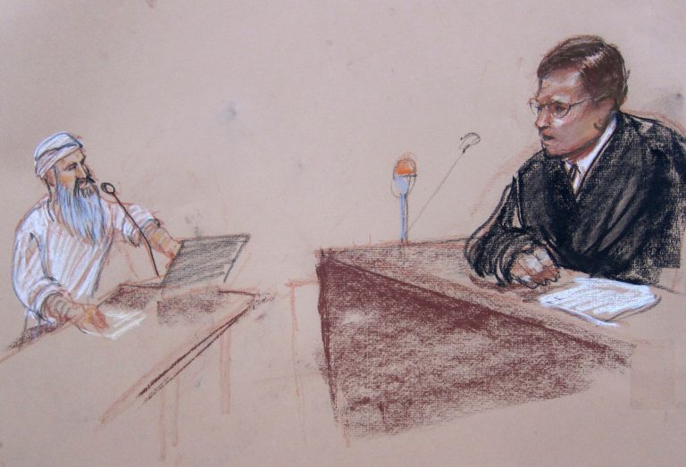 In this Pentagon-approved sketch by court artist Janet Hamlin, presiding judge, Navy Capt. J. Kirk Waits addresses Hadi al Iraqi, who presses a button on his microphone so he can respond, during his arraignment at the Guantanamo Bay U.S. Naval Base in Cuba, Wednesday, June 18, 2014. Abd al-Hadi al-Iraqi was arraigned on five war crimes charges, largely for allegedly organizing attacks on U.S. and allied forces in Afghanistan. He faces up to life in prison. (AP Photo/Janet Hamlin, Pool)