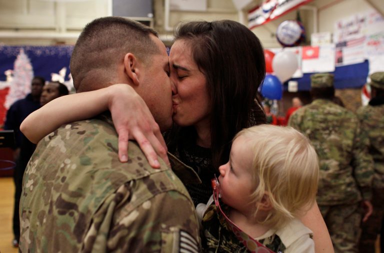 1st Lt. Aaron Dunn kisses his wife Leanne, holding their baby Emma, age 14 months, following an arrival ceremony for soldiers returning from a deployment in Afghanistan, at Ft. Carson, in Colorado Springs, Colo., before sun up Friday Nov. 30, 2012. 1st Lt. Dunn, with the 4th Brigade Combat Team, 4th Infantry Division, had not seen his wife and baby since he deployed in February. (AP Photo/Brennan Linsley)