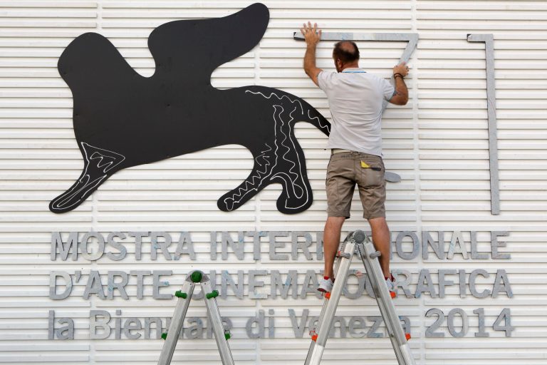 Enricco Masserdotti prepares a sign for the 71st edition of the Venice Film Festival in Venice, Italy, Monday, Aug. 25, 2014. The 71st edition of the festival opens on Wednesday, Aug. 27 and runs until Sept. 6. (AP Photo/David Azia)
