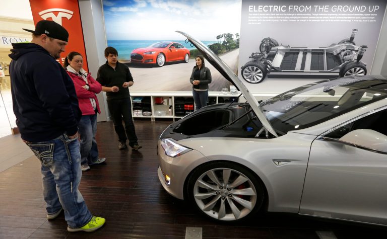FILE - In this March 17, 2014 file photo, Robert and Sarah Reynolds, left, check out a new Tesla all electric car with Tesla representatives John Van Cleave and Raven Rivera, right, at a Tesla showroom inside the Kenwood Towne Centre in Cincinnati. The Commerce Department releases durable goods for May on Wednesday, June 25, 2014. (AP Photo/Al Behrman)