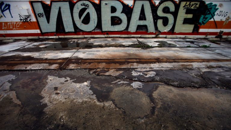   In this Sunday, Dec. 2, 2012 photo, graffiti against the U.S. military base is painted on a wall where a gas station used to stand across from the U.S. Air Force Kadena air base in Kadena, Okinawa, southwestern Japan. Okinawans are angry that Japan approved the deployment of 12 Osprey aircraft, which began in October, though the government has asked for additional assurances of the aircraft's safety. Washington said the Osprey is safe and is needed to ensure regional security. (AP Photo/Junji Kurokawa)  