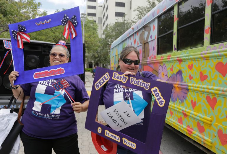 Nurses Shelley Pagan-Jones, left, and Diane Poirier, right, who are members of the SEIU union, board a bus to go to an early voting precinct, on the first day of early voting in Miami-Dade County for the general election, Monday, Oct. 24, 2016, in Miami. They were attending an early voting celebration outside of Jackson Memorial Hospital that was organized by local unions and immigrant groups to encourage people to vote during the two week early voting period. (AP Photo/Lynne Sladky)