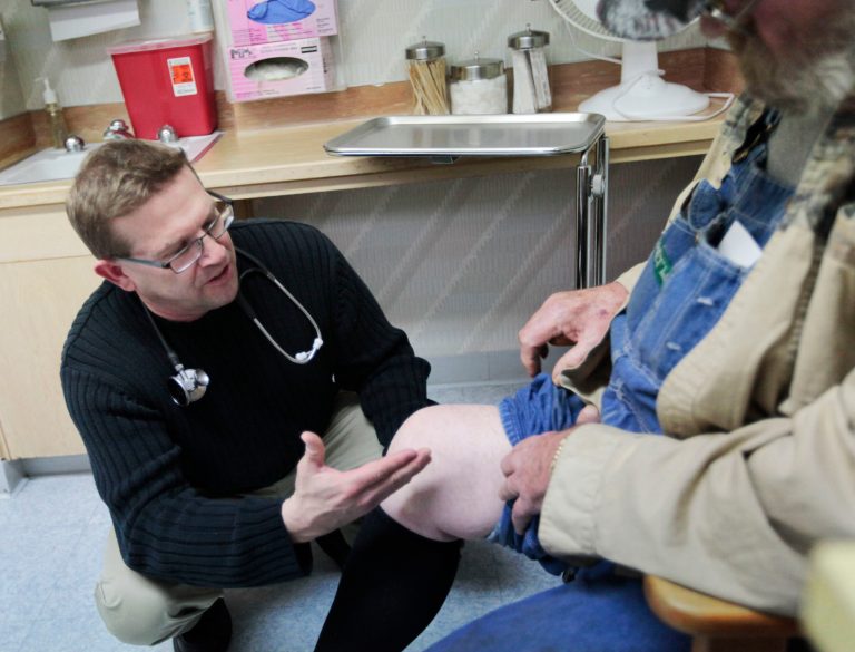 In this Tuesday, Dec. 13, 2011 file photograph, physician assistant Jon Bigler looks at a patient's leg at Ashland Health Center in Ashland, Kan. (AP Photo)Â 