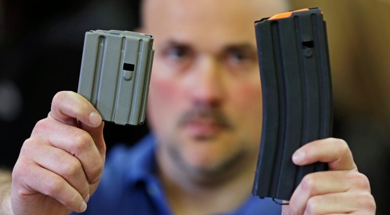The owner of an ammunition manufacturing company holds up a 10 round, left, and a 30 round, right, magazine for the AR-15 rifle. (AP Photo/Charles Krupa)