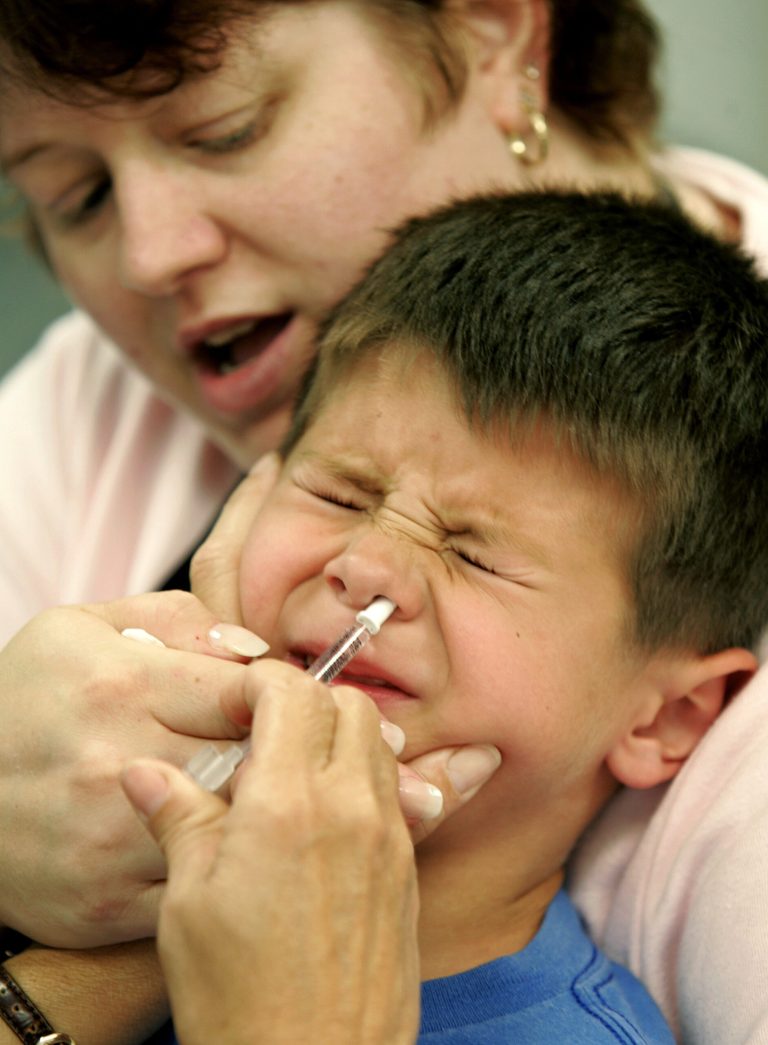 In this Tuesday, Oct. 4, 2005 file photo, Eric Krex, 6, reacts as he is held by his mother, Margaret, while a nurse gives him a FluMist influenza vaccination in St. Leonard, Md. According to a study released Wednesday, Oct. 8, 2014, members of the military who squirted vaccine up their noses were as well-protected as others who got it from health care workers. There's no reason civilians couldn't do the same, especially for children who might be less scared if vaccine was given by mom or dad, the study leader said. (AP Photo/Chris Gardner)