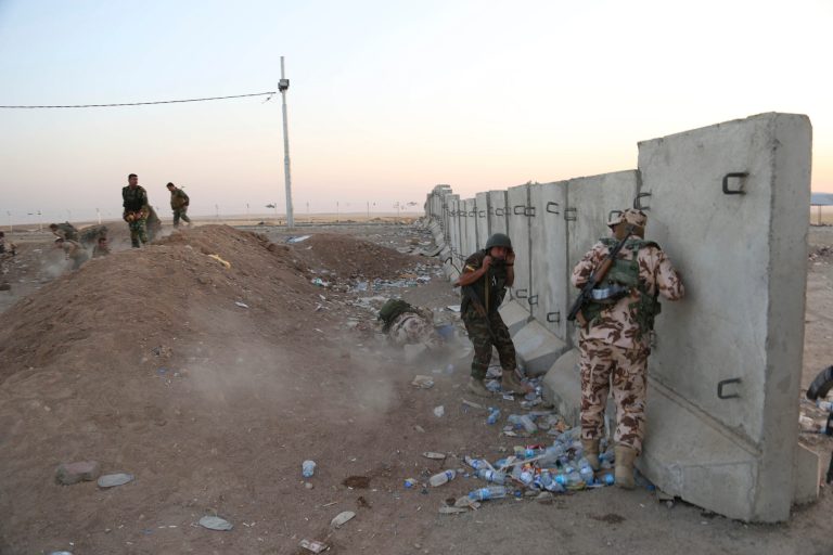 In this Aug. 8, 2014, file photo, Kurdish Peshmerga fighters take cover during airstrikes targeting militants of the Islamic State group near the Khazer checkpoint outside of the city of Irbil in northern Iraq. (AP Photo/Khalid Mohammed, File)