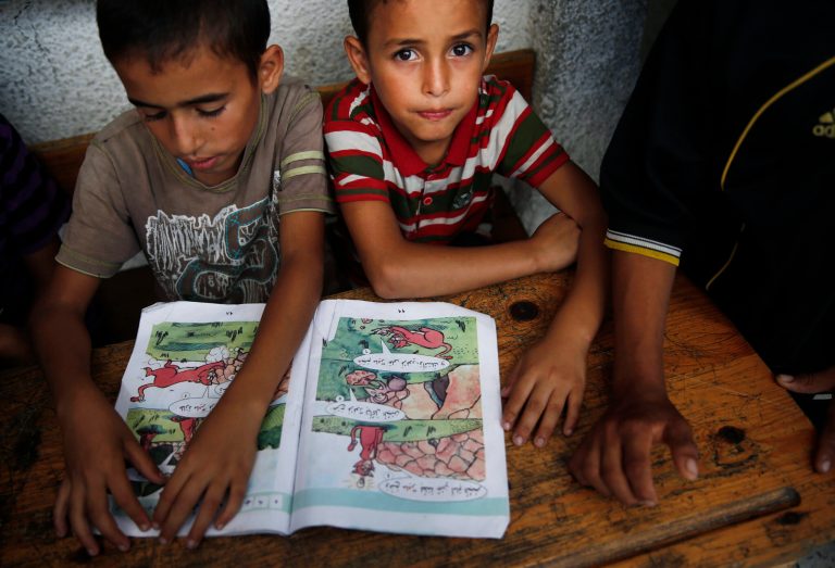 Palestinian boys read at a United Nations school where dozens of families have sought refuge after fleeing their homes following heavy Israeli forces' strikes in Beit Hanoun, northern Gaza Strip, Saturday, July 19, 2014. (AP Photo/Lefteris Pitarakis)