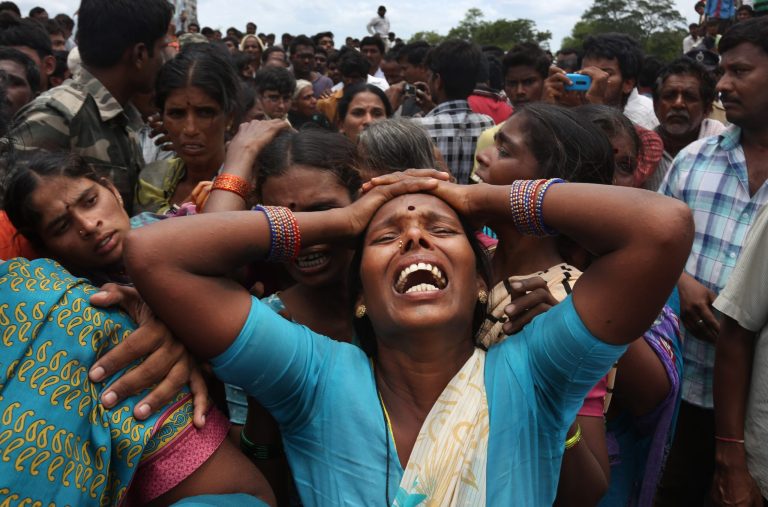 A relative of a victim cries at the site of a train that crashed into a school bus in Medak district in the southern Indian state of Telengana, Thursday, July 24, 2014. Twelve children were killed Thursday when the train crashed into a school bus at an unmanned railroad crossing in southern India, police said. There are hundreds of unmanned crossings across the country, especially in remote areas. (AP Photo/Mahesh Kumar A.)