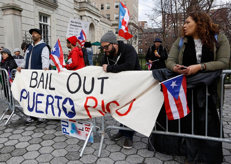 Protesters express their opposition to the fact the the Federal Reserve bank bailed out Wall Street but not Puerto Rico outside International House, Thursday, April 7, 2016, in New York. (AP Photo/Kathy Willens)