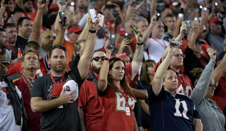 New England Patriots and Tampa Bay Buccaneers fans shine flashlights during a moment of silence for the victims of the Las Vegas shootings before an NFL football game Thursday, Oct. 5, 2017, in Tampa, Fla. (AP Photo/Phelan Ebenhack)