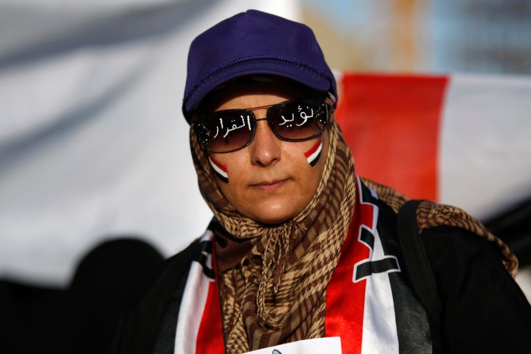   A female protestor with Yemen's flag painted on her face and Arabic writing on sunglasses that reads, 