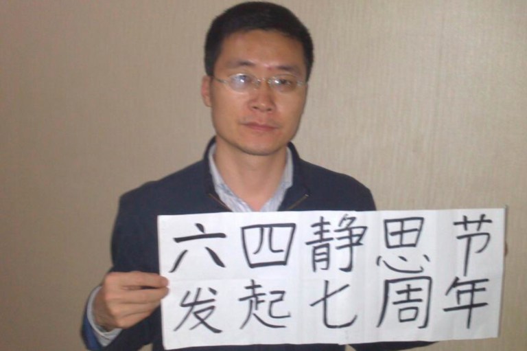 In this photo taken on April 26, 2014 and released by Wang Yanfang, wife of lawyer Tang Jingling, Tang holds a placard with Chinese characters 