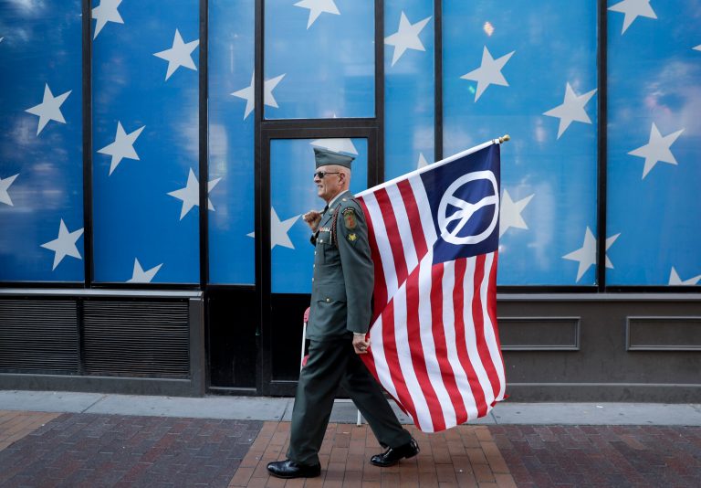 A protester carrying a peace flag walks in downtown Cleveland, Sunday, July 17, 2016, in preparation for the Republican National Convention that starts Monday. (AP Photo/Patrick Semansky)