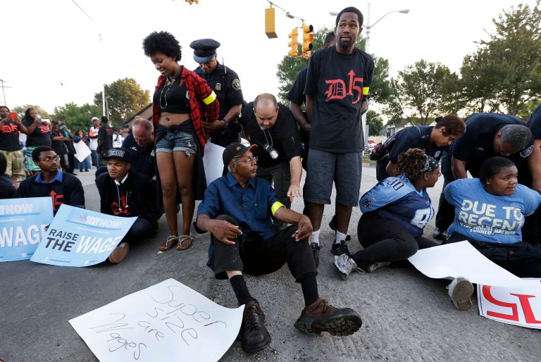 Police handcuff protesters blocking traffic on Mack Avenue in Detroit as part of a national protest to push fast-food chains to pay their employees at least $15 an hour Thursday, Sept. 4, 2014. Hundreds of workers from McDonald's, Taco Bell, Wendy's and other fast-food chains are expected to walk off their jobs Thursday, according to labor organizers of the latest national protest to push the companies to pay their employees at least $15 an hour. (AP Photo/Paul Sancya)