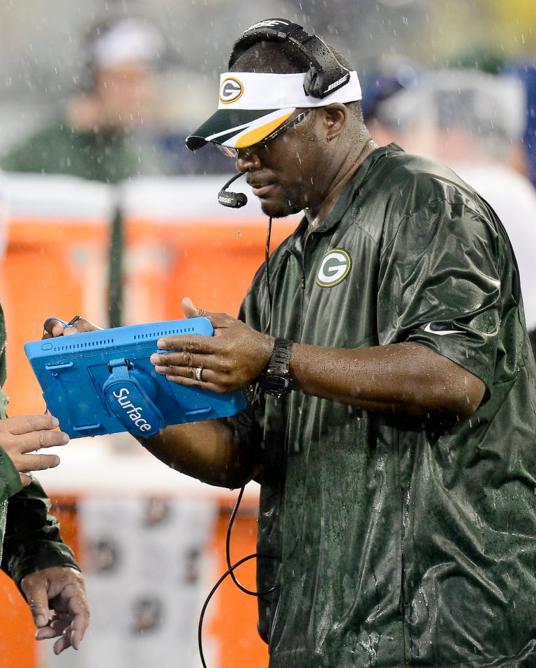 In this Aug. 9, 2014 photo, Green Bay Packers wide receivers coach Edgar Bennett uses a computer pad in a rainstorm during a preseason NFL football game against the Tennessee Titans in Nashville, Tenn. The tablets, designed to survive all sorts of weather, are equipped to look at still photos of game action. (AP Photo/Mark Zaleski)