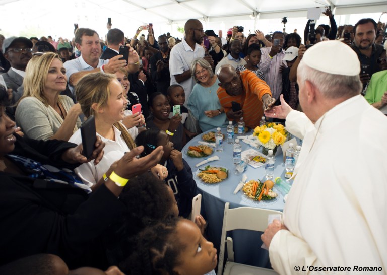 In this photo taken Thursday, Sept. 24, 2015, Pope Francis is greeted as he arrives at a lunch for homeless people who are regularly fed by Catholic Charities, at St. Patrick's Church in Washington, following his address to a joint meeting of Congress on Capitol Hill. (L'Osservatore Romano/Pool Photo via AP)