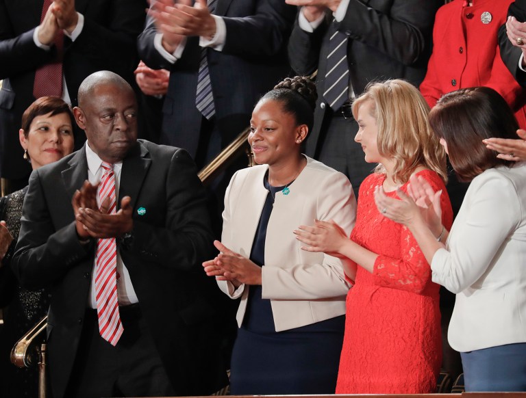 Denisha Merriweather, center, stands up after being acknowledge by President Donald Trump during his address to a joint session of Congress. On the left applauding is Jamiel Shaw, Sr. (AP Photo/Pablo Martinez Monsivais)
