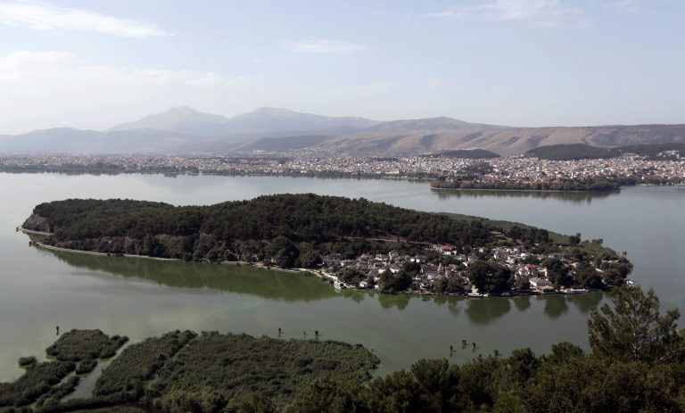 This Friday, Aug. 22, 2014, aerial photo shows a view of Pavmotis Lake, with the lake isle and city of Ioannina, in northwestern Greece. The country's severe financial crisis has forced businesses to seek fish exports in eastern Europe and promote the area as a day-trip destination. (AP Photo/Thanassis Stavrakis)