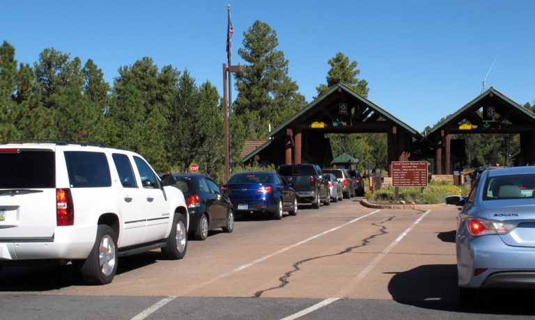   In this Sept. 30, 2013, photo, cars line up at Grand Canyon National Park's South Rim entrance before the park was closed on Oct. 1 due to the partial government shutdown. Americans are finding that âthe governmentâ entails a lot more than the stereotype of faceless D.C. bureaucrats cranking out red tape. (AP Photo/Felicia Fonseca)  