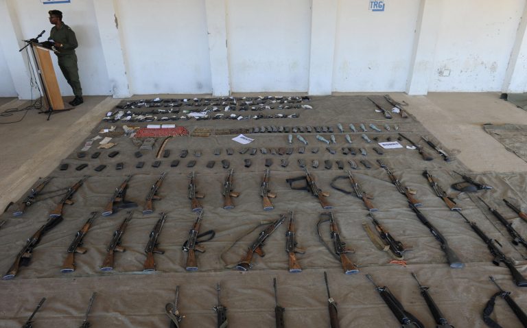 A Lesotho Defence Force member displays arms and ammunition confiscated from police at army barracks in Maseru, Lesotho, Monday, Sept. 1, 2014. Southern Africa's regional body said Monday it will send an envoy and an observer team to Lesotho to help restore stability and security in the mountainous kingdom where military actions over the weekend caused the prime minister to flee. (AP Photo)