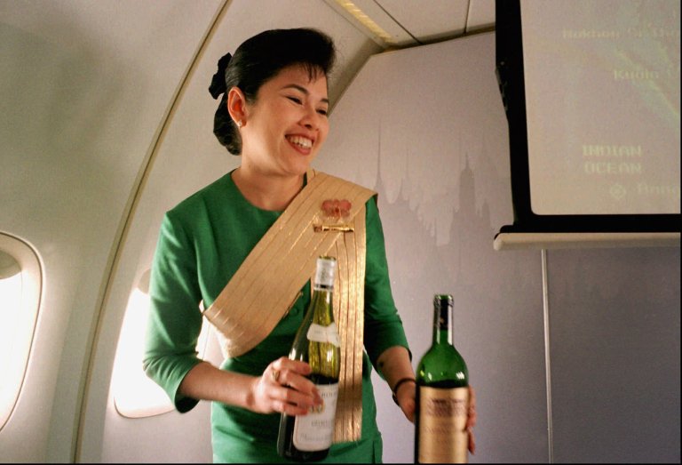   FILE - In this Dec. 14, 1996, file photo, a Thai Airways International airline flight attendant offers a passenger a selection of wine during a flight from Singapore to Bangkok. Airlines have found a way to take the edge off the stress of flying and make a few extra bucks along the way: fancy new cocktails, craft beers and elegant wines. (AP Photo/Richard Vogel)  