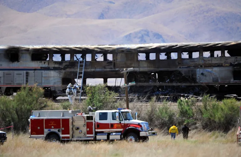 FILE - In this June 24, 2011 file photo, burned Amtrak passenger cars are left after the train was struck by a semitrailer near Fallon, Nev. A federal jury in Reno on Wednesday, Sept. 17, 2014 awarded $4.5 million to Amtrak and $210,777 to Union Pacific Railroad for damages resulting from John Davis Trucking Co.'s negligence when one of its trucks slammed into the side of the passenger train. U.S. District Judge Howard McKibben has put the judgment on hold until Sept. 29 to consider adding up to another $1 million or more in attorney fees and interest to the award to the railroad companies. (AP Photo/Reno Gazette Journal, Liz Margerum, File)