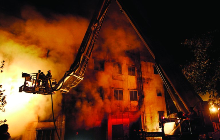 FILE - In this Nov. 24, 2012 file photo, Bangladeshi firefighters battle a fire at a garment factory in the Savar neighborhood in Dhaka, Bangladesh. A Bangladesh government committee investigating the garment factory fire that killed 112 people last month said in its findings Monday, Dec. 17, 20112 that the blaze was sabotage, probably by someone who worked there. But the panel said that no matter who set the fire, the owner of the factory also should be punished for the deaths because he neglected worker safety. (AP Photo/Hasan Raza, File)
