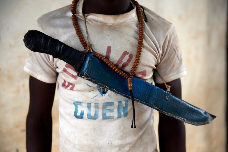In this April 15, 2014 photo, an Anti-Balaka Christian fighter stands on the front of a looted Muslim store in Guen, some 250 kilometers north of Bangui, Central African Republic. As U.N. peacekeepers prepare to go into the Central African Republic to take over a regional mission, the death toll since fighting between Muslims and Christians started in December underscores how the aid is coming too late for thousands of victims. (AP Photo/Jerome Delay)