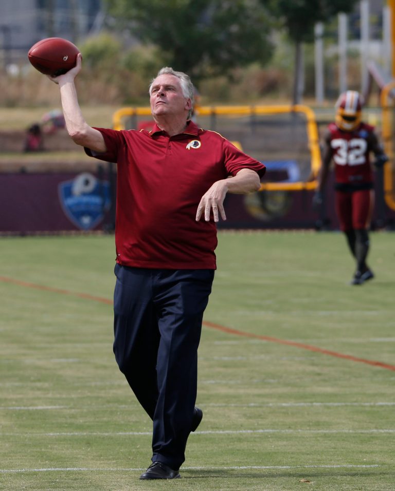 Virginia Gov. Terry McAuliffe tosses a pass during a visit to the Washington Redskins' NFL football training camp in Richmond,. Va., Thursday, July 27, 2017. (AP Photo/Steve Helber)