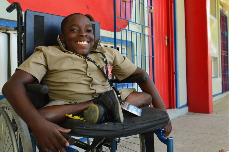 In this Oct. 7, 2014 photo, seventh-grader Andre Coleman poses in his wheelchair at his new school in the Mona neighborhood of Kingston, Jamaica. The hard-working 12-year-old with a big personality has a disabling spinal condition that does nothing to stop him from enthusiastically joining in football games with able-bodied peers. Even as they grapple with overcoming numerous challenges, hopes for the future are rising among many disabled youngsters.in Jamaica. Last week, lawmakers passed a watershed law that will, among other things, prohibit workplace discrimination and create a special tribunal to rule on complaints made by disabled citizens. (AP Photo/David McFadden)