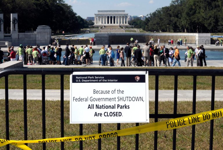 FILE - In this Oct. 2, 2013 file photo people visit the closed World War II Memorial on the National Mall in Washington, despite signs stating that the national parks are closed due to the federal shutdown. The Lincoln Memorial is in the background. The shutdown is transforming a musty debate over the role of government in America into a coast-to-coast, prime-time reality show. With landmarks closed, paychecks delayed and workers furloughed, Americans are drawing dueling lessons from the rippling effects of the partial shutdown: either the disruptions show that the feds are way too involved in people's lives, or that the government does a lot of vital things that people take for granted. (AP Photo/Susan Walsh, File)