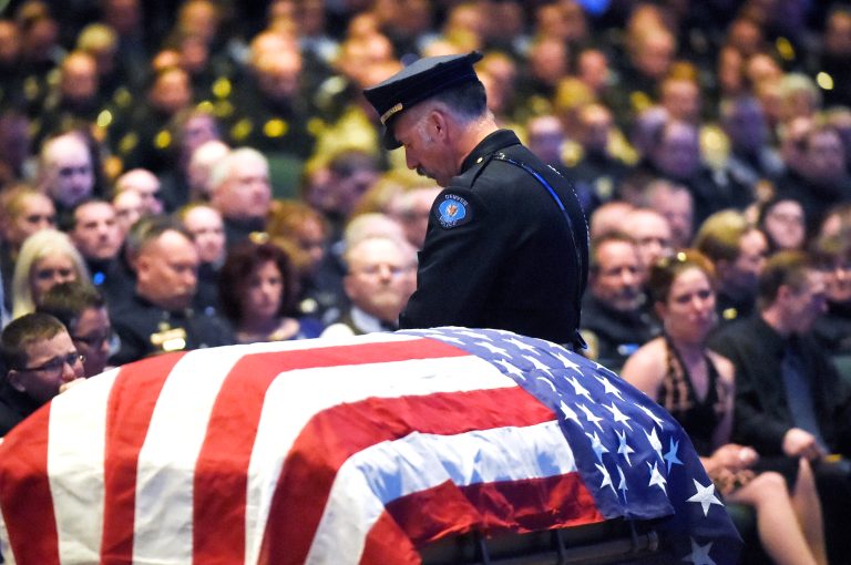 A Denver police officer stands watch over the flag draped casket at the memorial service for Park County Deputy Corporal Nate Carrigan at Faith Bible Chapel in Arvada, Colo., Monday, March 14, 2016. (Helen H. Richardson/The Denver Post via AP)