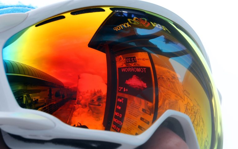 The forecast for tomorrow's temperature is reflected in the ski goggles of a volunteer at the Sochi 2014 Winter Olympics, Tuesday, Feb. 11, 2014, in Krasnaya Polyana, Russia. Warm temperatures in the mountains made the snow too soft and caused the cancellation of Women's downhill training on Tuesday.  (AP Photo/Luca Bruno)
