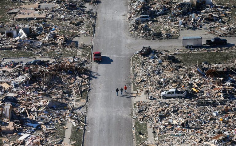 FILE - This Monday, Nov. 18, 2013 aerial file photo shows people walking down a street where homes once stood that were destroyed by a tornado that hit the western Illinois town of Washington. Mayor Gary Manier said the city has issued more than 600 building permits for the more than 1,000 badly damaged or destroyed homes. But construction was slowed by the harsh winter and for many is just beginning. (AP Photo/Charles Rex Arbogast, File)