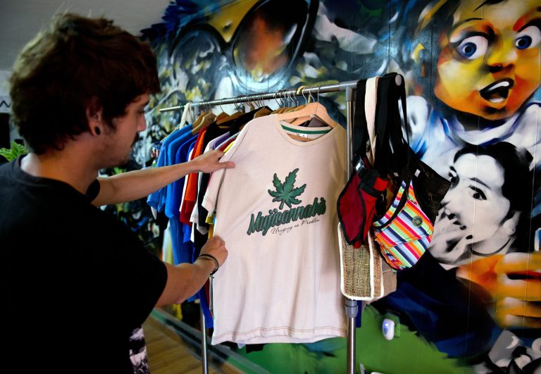 A shopper looks at a T-shirt decorated with a marijuana leaf and the word 